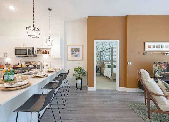 A kitchen with white countertops and black chairs.