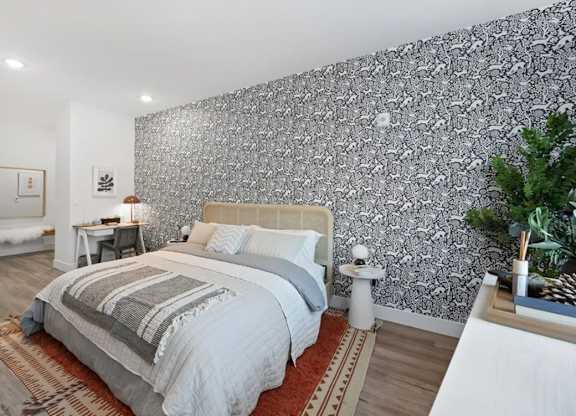 A bedroom with a large bed and a patterned wallpaper.