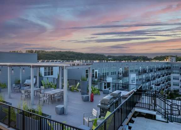 A rooftop patio with a table and chairs overlooks a cityscape.