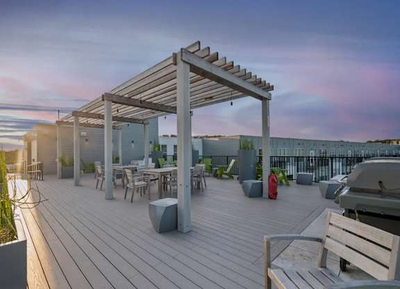 A wooden deck with a pergola and seating area overlooking a body of water.