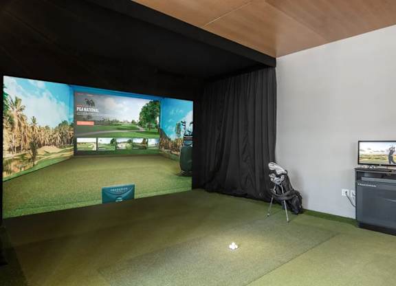 A room with a golf simulator screen and a TV.