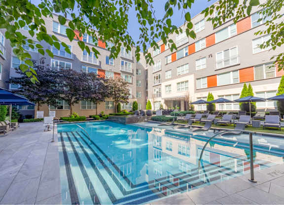 A swimming pool surrounded by apartment buildings and trees.