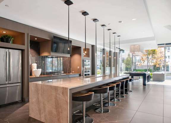 A modern kitchen with a long counter and stools.