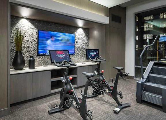 A modern gym with exercise bikes and a television.