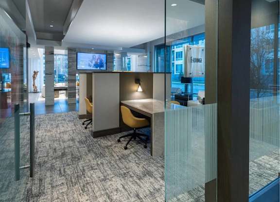A modern office space with glass partitions and a grey carpet.