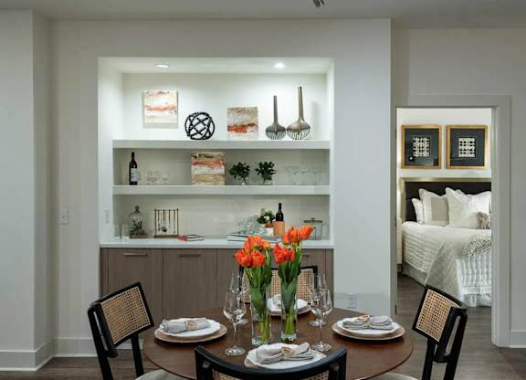 A dining room with a table set for two and a bed in the background.