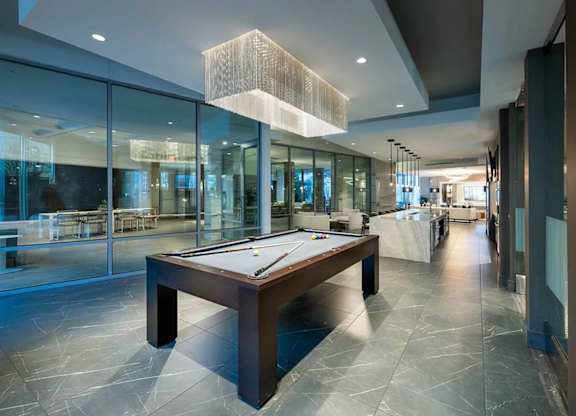 A pool table is in the middle of a room with a glass wall.
