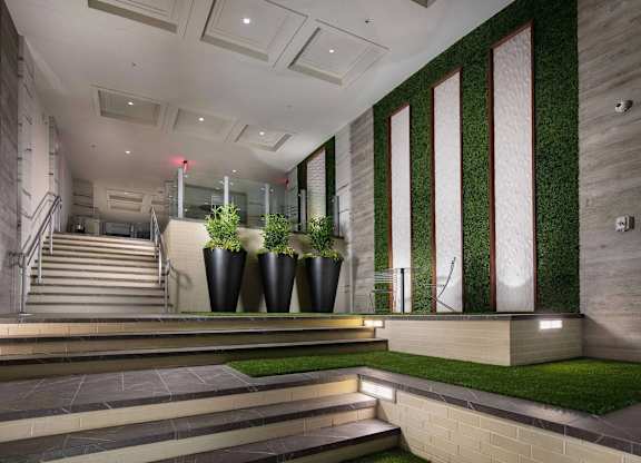 A staircase with a glass railing and a green plant on the side.