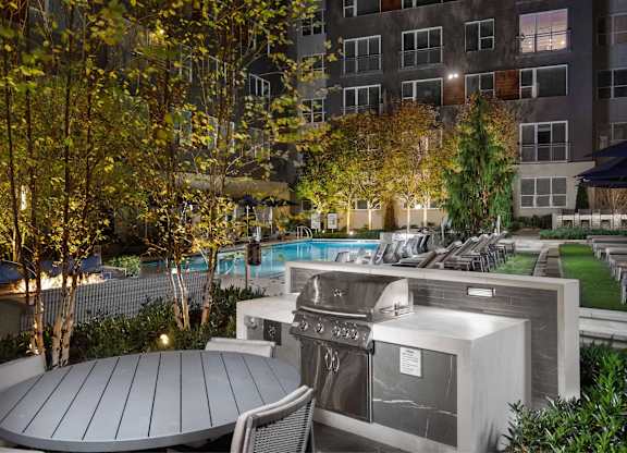 A BBQ grill is set up on a patio next to a pool.