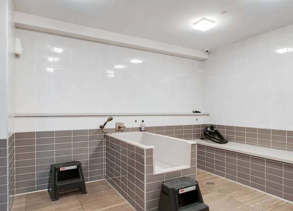 A bathroom with a white tub and grey tiles.