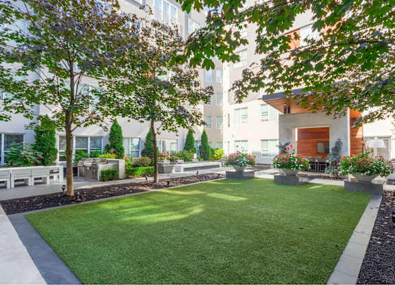 A well-maintained lawn area with a bench and trees in front of a building.