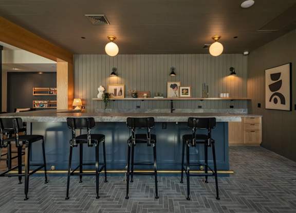 A modern kitchen with a bar area featuring black stools and a marble countertop.