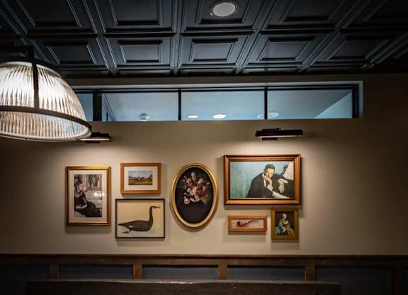 A pool table with a light hanging above it and pictures on the wall.
