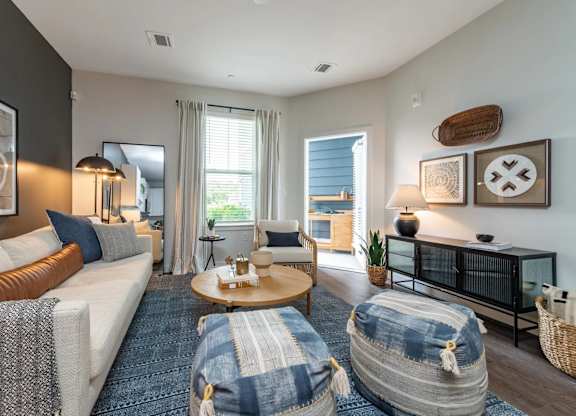 A living room with a white couch, a coffee table, and a large window.