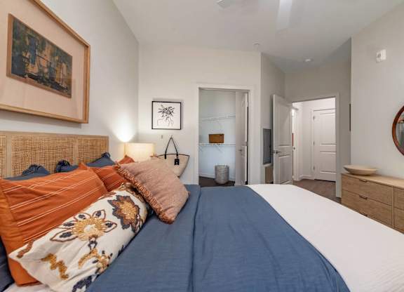 A bedroom with a bed, a mirror, and a painting on the wall.