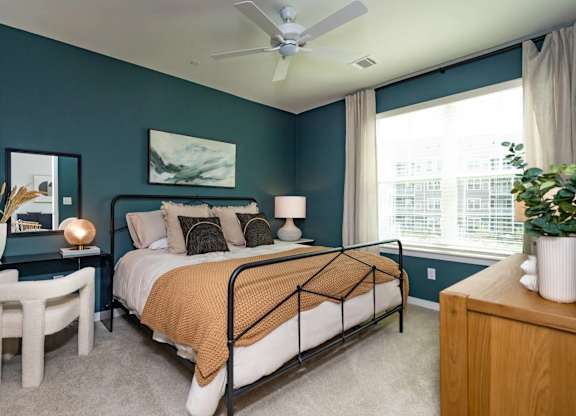 A bedroom with a bed, a side table, and a ceiling fan.