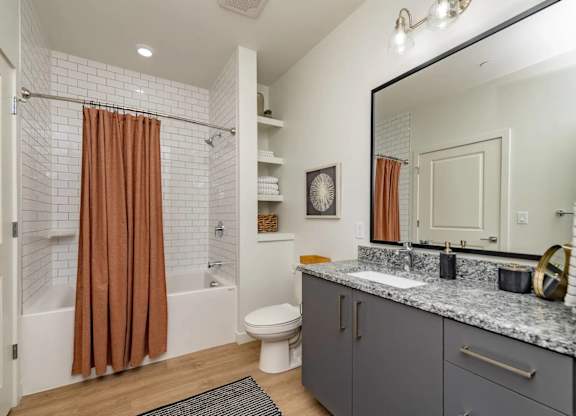 A bathroom with a brown shower curtain and a white tiled shower.