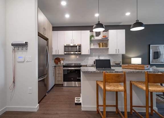 A kitchen with a refrigerator, stove, and bar stools.
