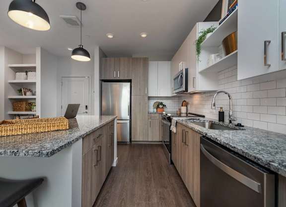 A modern kitchen with a granite countertop and stainless steel appliances.