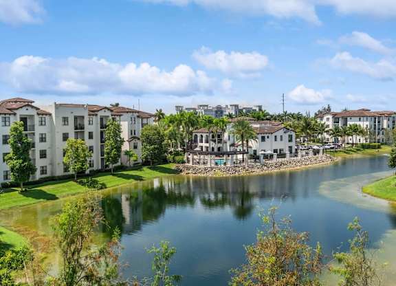 A serene lake surrounded by residential buildings under a clear blue sky.