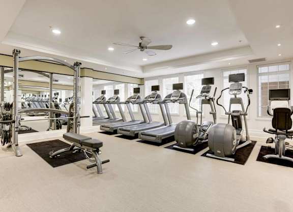 A spacious gym with a variety of equipment including treadmills, elliptical machines, and weight machines.