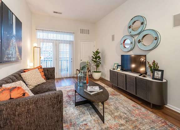A living room with a brown couch, a coffee table, and a large painting on the wall.