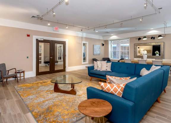 A blue couch with a glass table in front of it.