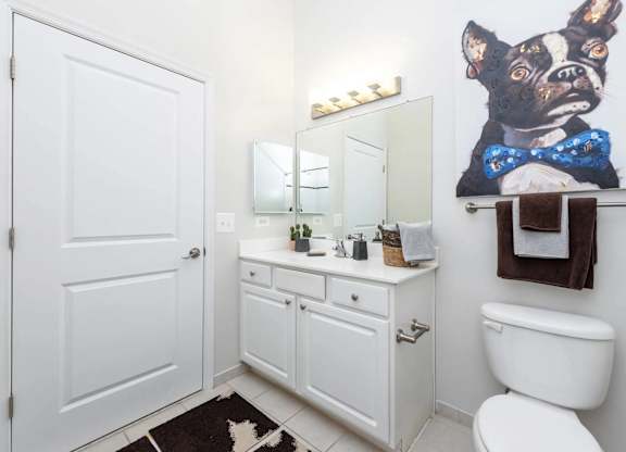 A white bathroom with a dog picture on the wall.