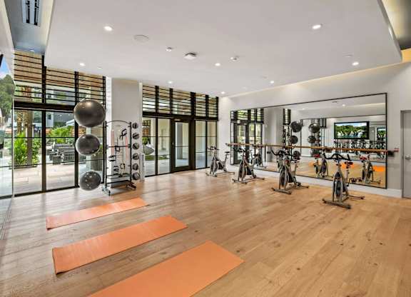 A gym with exercise equipment and yoga mats.