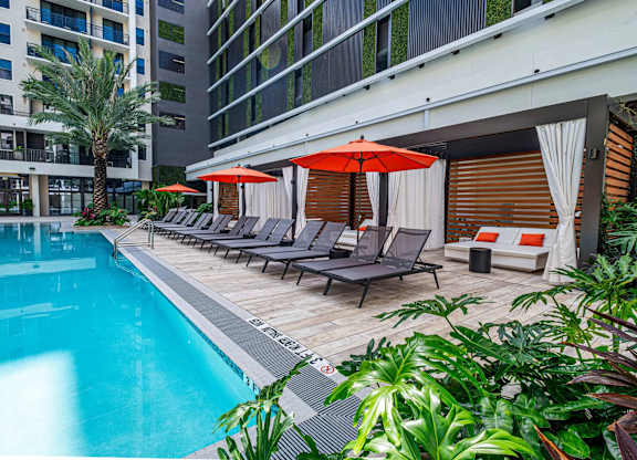A pool area with sun loungers and umbrellas.