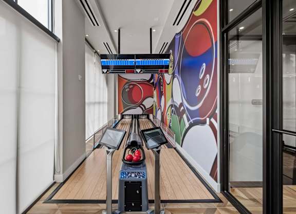 A bowling alley with a row of lanes and a colorful mural on the wall.