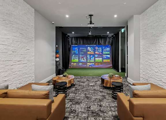 A room with a large screen and comfortable seating.