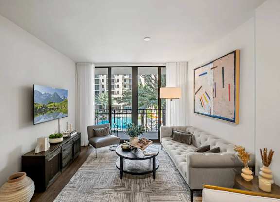 A living room with a grey couch, a coffee table, and a painting on the wall.