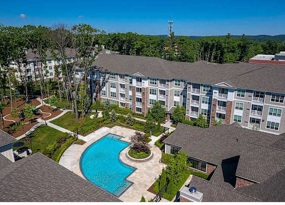 A large apartment complex with a swimming pool in the foreground.