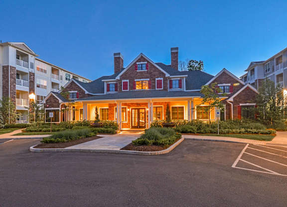A large building with a red roof and a parking lot in front.