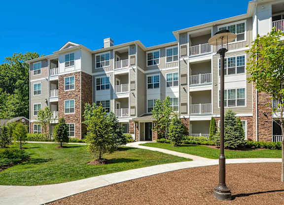 A large apartment complex with a well-maintained lawn and trees.