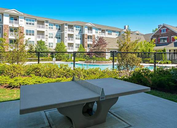 A table tennis table is in the foreground of a residential area with apartment buildings in the background.