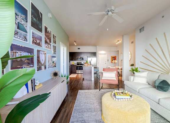 A living room with a white couch and a yellow ottoman.