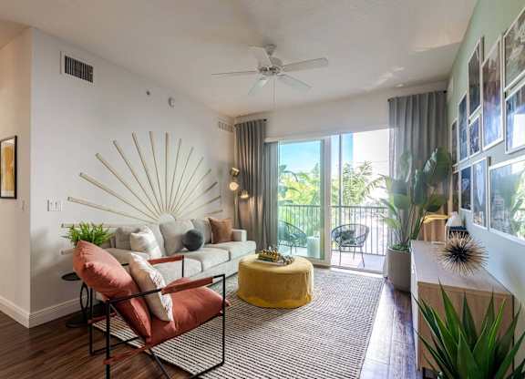 A living room with a yellow ottoman and a red chair.