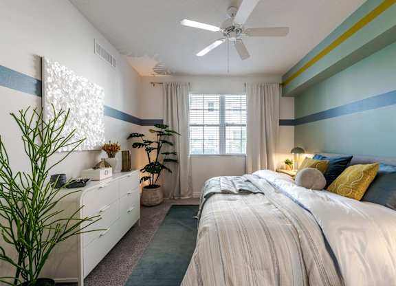 A bedroom with a large bed and a ceiling fan.