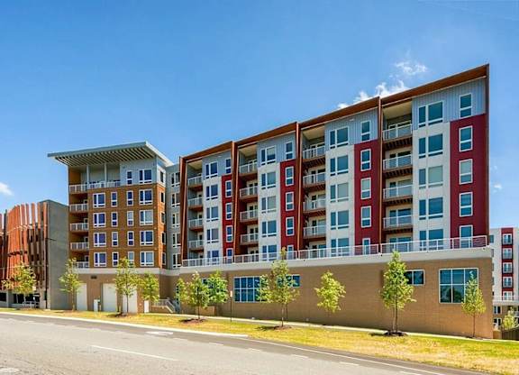 A large multi-story apartment building with red and white balconies.