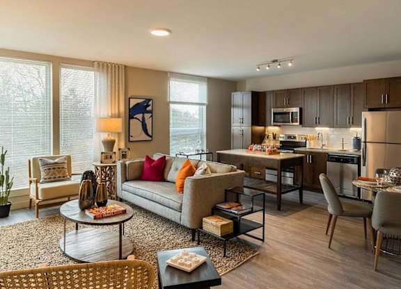 A modern living room with a grey sofa, a coffee table, and a dining table with chairs.