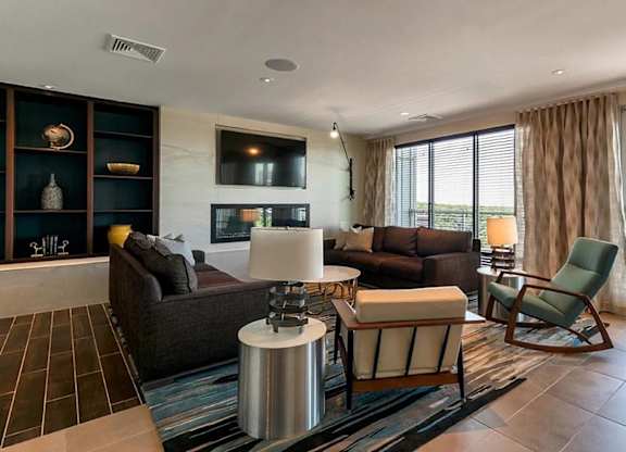 A living room with a brown couch, a white table, and a green chair.