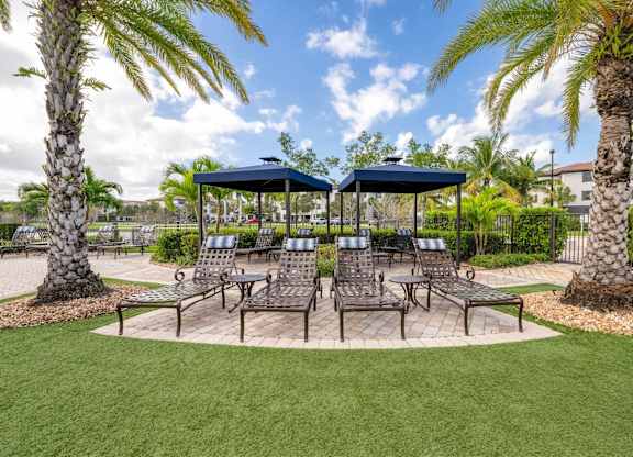 A sunny day at the park with a gazebo and palm trees.