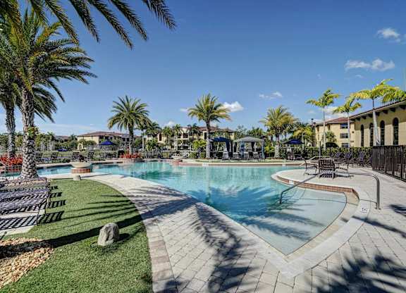 A pool surrounded by palm trees and a sunny sky.