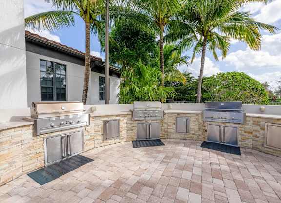 A patio with a stone wall and four grills.