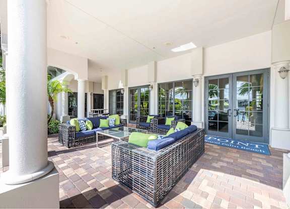 A patio with a white column and a wicker sofa.