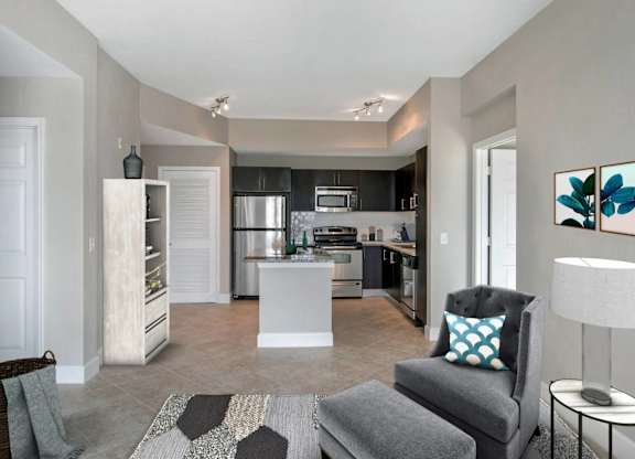 A modern kitchen with a grey chair and a white island.