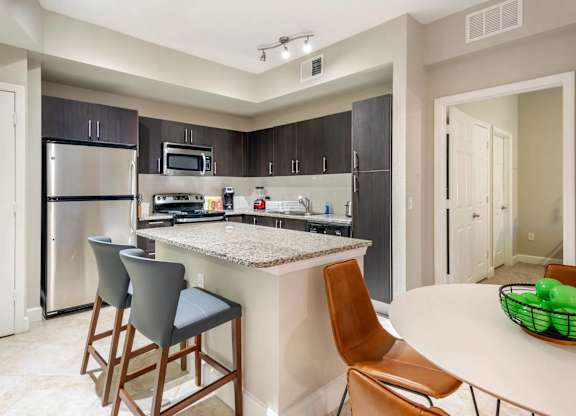 A kitchen with a bar and chairs.