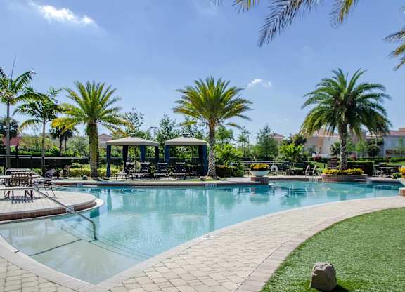 A large swimming pool surrounded by palm trees and lounge chairs.